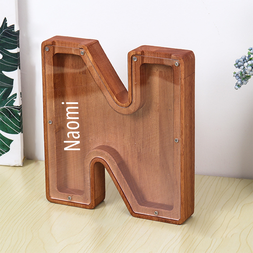 MadeMine personalised wooden piggy bank shaped as letter N with clear acrylic front and Naomi name