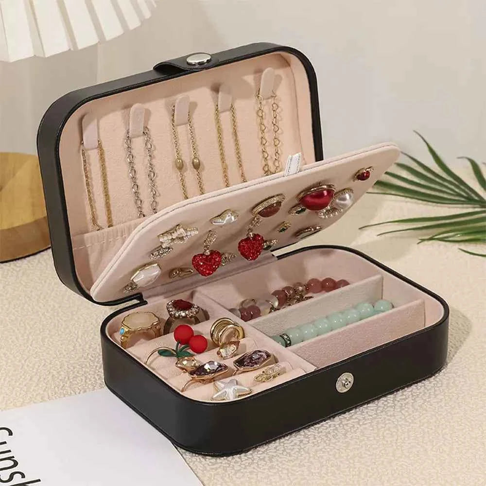 MadeMine black custom leather travel jewellery case open showing padded pink interior with rings earrings bracelets and necklaces