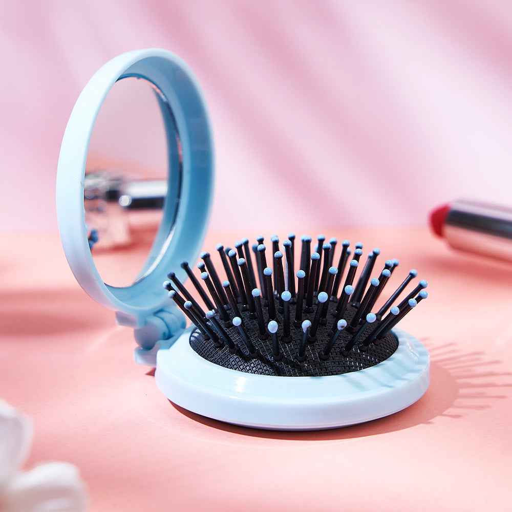 MadeMine personalized foldable mirror brush in light blue with soft bristles on pink background