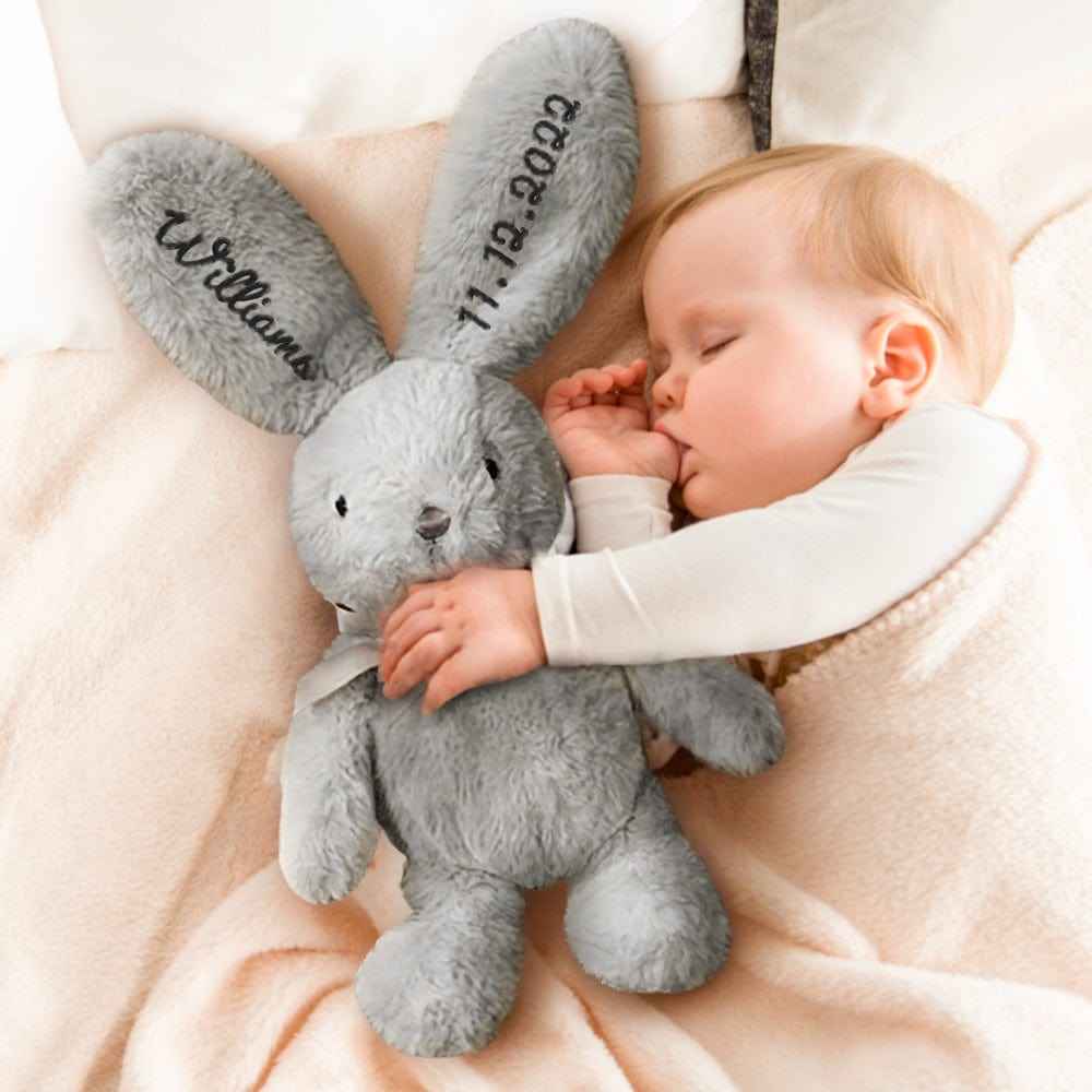 MadeMine personalised bunny rabbit toy grey plush with embroidered name and date cuddled by sleeping baby