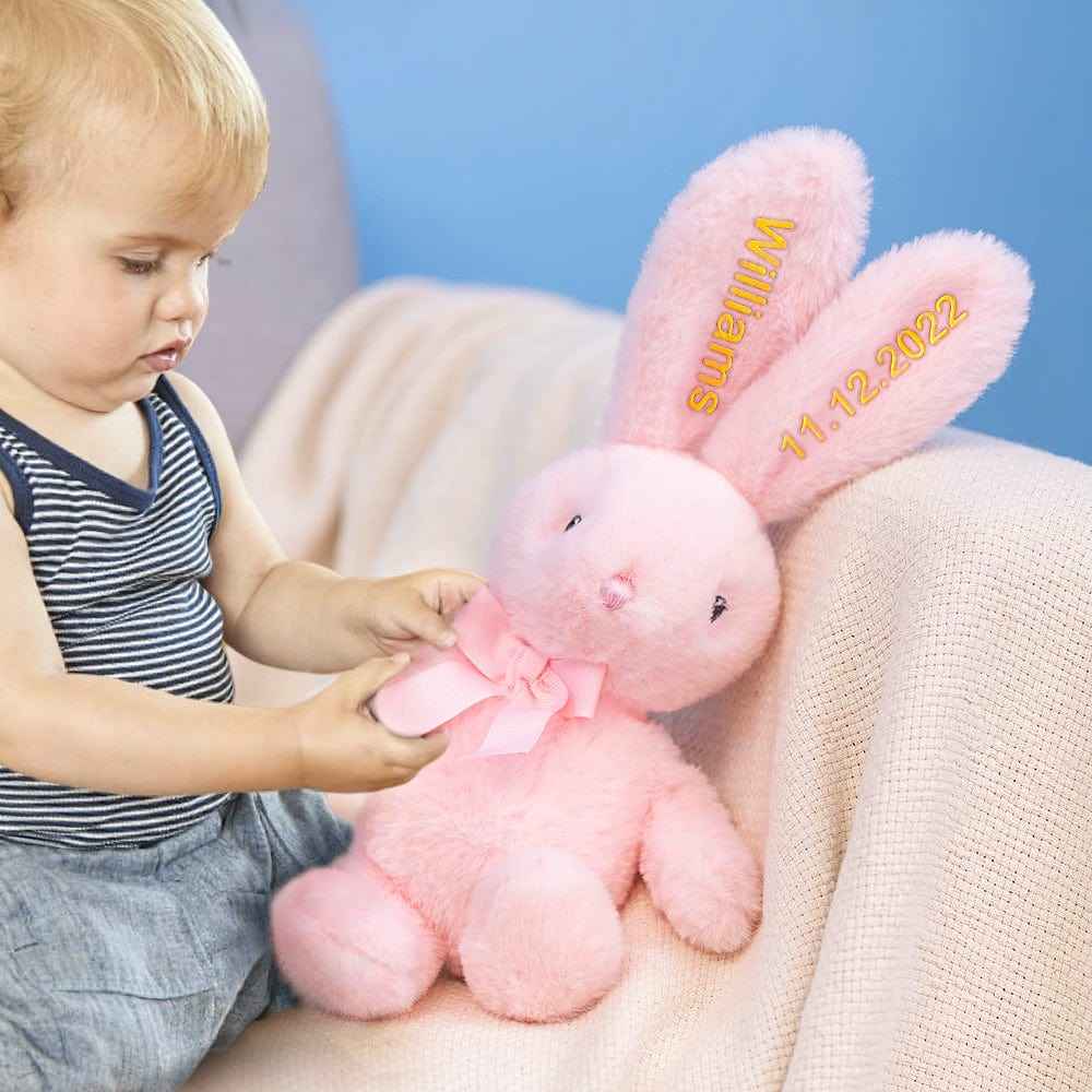 Toddler playing with pink personalised bunny rabbit toy with embroidered name and date on ears